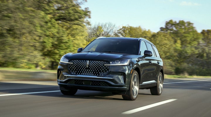 A 2026 Lincoln Black Label™ Aviator® SUV is being driven down a road lined with trees. | Napleton River Oaks Lincoln in Calumet City IL