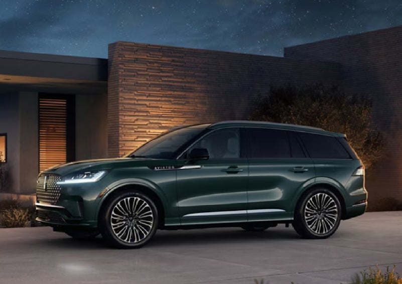 A green 2027 Lincoln Aviator® SUV is parked outside a contemporary home. | Napleton River Oaks Lincoln in Calumet City IL