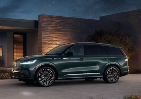 A green 2027 Lincoln Aviator® SUV is parked outside a contemporary home. | Napleton River Oaks Lincoln in Calumet City IL