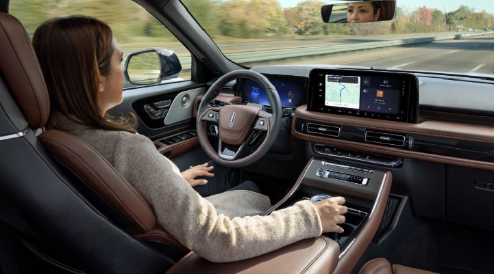 A 2027 Lincoln Aviator® SUV is being driven hands-free on a highway lined with trees. | Napleton River Oaks Lincoln in Calumet City IL