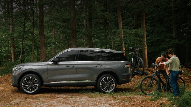 A father and son load e-bikes on a bike rack attached to a 2027 Lincoln Aviator® SUV. | Napleton River Oaks Lincoln in Calumet City IL
